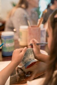Children painting ceramics in a pottery workshop, enjoying creativity and bonding.