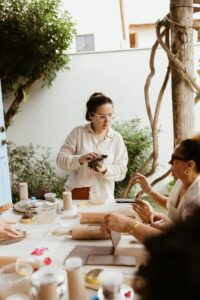 Group of adults participating in an outdoor pottery workshop, creating and sharing joy.