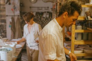Two ceramic artists focused on their work in a pottery studio, showcasing creativity.